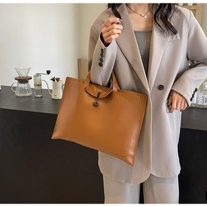 Detailed side view of a brown matte leather tote bag with envelope flap and cord closure