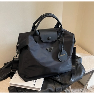Détail du grand cabas en nylon noir avec logo triangle en métal et rabat à bouton-pression