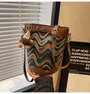 Detailed close-up of a bohemian knitted bucket bag with colorful wavy patterns and leather trim