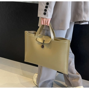 Detail of olive green tote bag featuring contrast white stitching and button closure