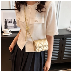 Détail du mini sac bandoulière matelassé doré avec chaîne d'or et boucle métallique ronde