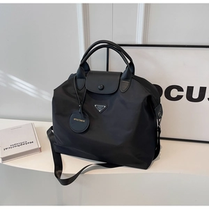 Détail du sac cabas en nylon noir avec logo triangle argenté et bandoulière amovible