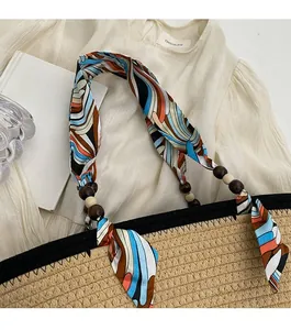 Detail of colorful geometric strap and wooden beads on a straw tote bag for women
