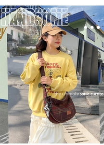 Détail d'un sac seau vintage à carreaux avec breloque lapin et bandoulière large