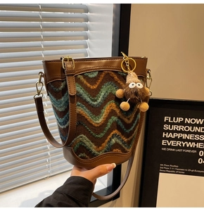 Detail of bohemian bucket bag featuring wave-pattern knit fabric and plush monster charm