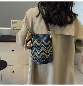Knitted bucket bag with wave pattern and cute plush charm on a beige trench coat
