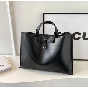 Detail view of large black minimalist tote bag with smooth texture and flip buckle closure