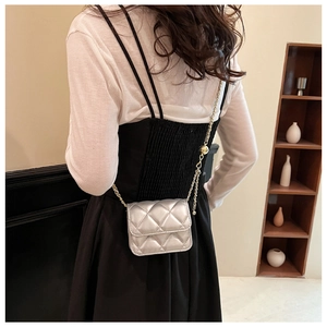 Mini sac bandoulière argenté matelassé avec chaîne dorée porté par un mannequin