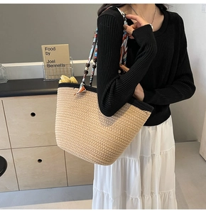 Detail of straw tote bag featuring contrast black trim, silk scarf handle, and wooden beads