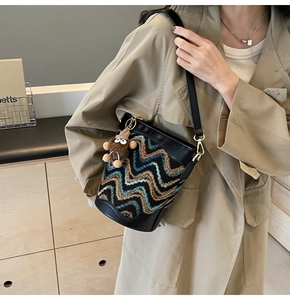 Detail of chevron woven bucket bag with leather trim and brown plush monster charm