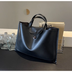 Close-up of black PU leather tote bag with unique brown button and elastic rope closure