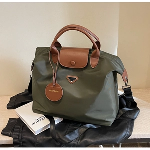 Détail du cabas en nylon vert armée avec poignées en cuir marron et logo métal triangulaire