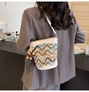 Detail of woven bucket bag with blue and brown wave patterns and a cute monster plush charm