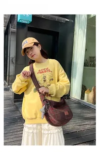 Sac seau à carreaux marron porté par un mannequin avec un sweat-shirt jaune vif