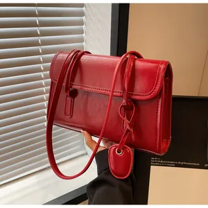 Detail showing red glossy faux leather shoulder bag with matching pendant charm
