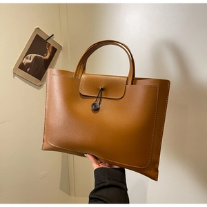 Detailed view of caramel leather tote bag showing fine texture and decorative stitching