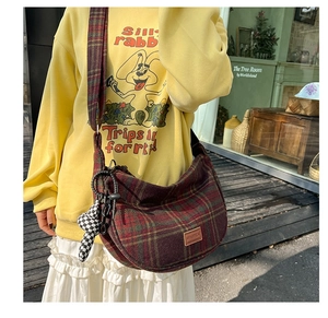 Détail du sac seau en nylon à carreaux rouges avec bandoulière assortie et charm peluche