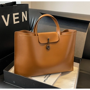 Detail of caramel leather tote bag with vintage wooden button closure and gift box display
