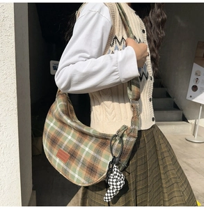 Mannequin portant un sac hobo à carreaux vert et marron avec pendentif damier en peluche