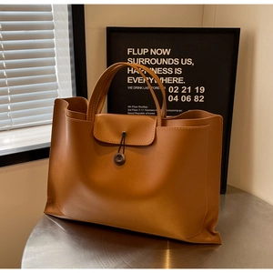 Close-up of caramel brown leather tote bag with wood button closure and fine stitching