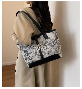 Detail of floral print tote bag with leather handles and metal buckle on beige coat
