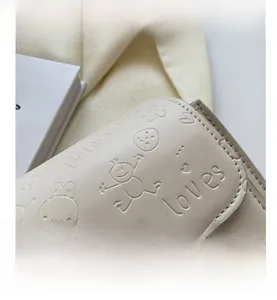 Detail of cream leather shoulder bag with embossed cartoon bunnies and gold metal clasp