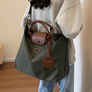 Sac fourre-tout en nylon vert olive avec anses en cuir marron porté par un mannequin