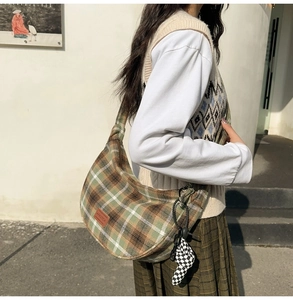 Détail du sac hobo à carreaux vert et beige avec une breloque poupée en damier