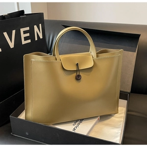 Detail of a green matte leather tote bag with white stitching in a black gift box