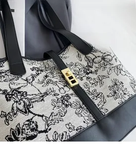 Close-up of golden metal clasp on Toile de Jouy canvas tote with leather trim