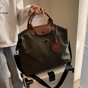 Grand sac cabas en nylon vert armée avec poignées en cuir sur valise blanche voyage