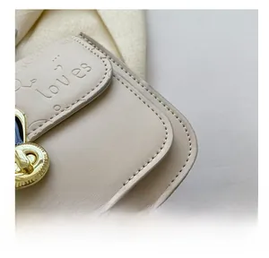 Close-up of premium cream leather bag showing heart embossing and golden twist lock