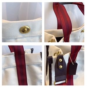 Detail view of white canvas tote featuring red striped straps and gold metal twist lock