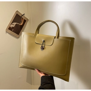 Detail of olive green tote bag featuring contrast stitching and a wood button closure