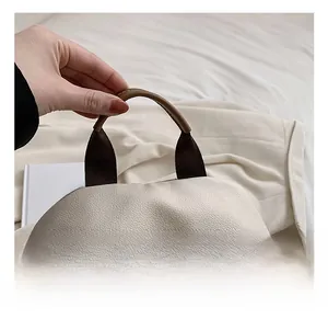 Détail du sac à dos en cuir grainé avec poignées marron et fermetures éclair argentées