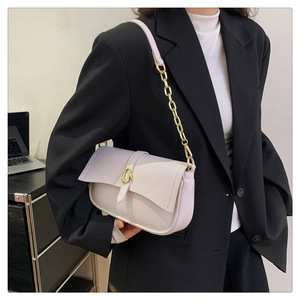 Dettaglio borsa in pelle martellata rosa chiaro con fibbia dorata e tracolla su blazer