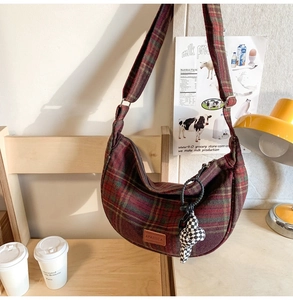 Détail du sac seau en nylon à carreaux rouges et verts avec pendentif en peluche