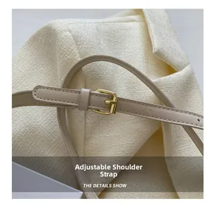 Detail view of adjustable beige leather shoulder strap with gold metal buckle