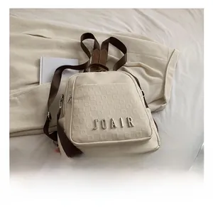 Vue détaillée du sac à dos beige avec gaufrage à carreaux et logo métallique élégant