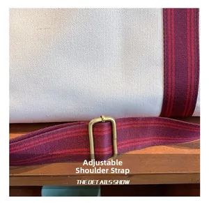 Detail of adjustable woven strap and metal buckle on canvas tote shoulder bag