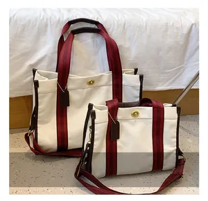 Detail view of canvas tote set with brown leather trim and red black striped handles