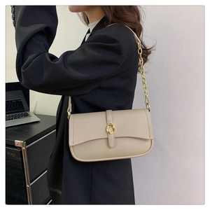 Dettaglio borsa a tracolla beige in pelle con fibbia dorata e cinturino a catena