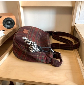 Détail du sac seau en laine à carreaux avec breloque lapin sur meuble en bois