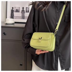 Detail of light green leather crossbody bag with bunny metal clasp and embossed pattern