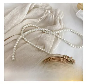 Detail of white pearl strap with woven floral basket and beige pleated fabric accent