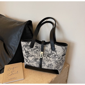 Detail of floral canvas tote bag with black leather trim and golden metal clasp