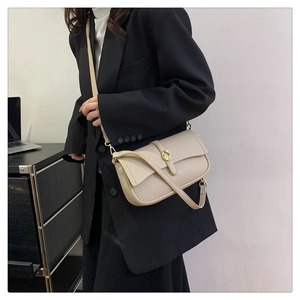 Dettaglio borsa a tracolla in pelle color crema con fibbia dorata indossata