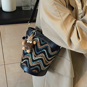 Vintage bucket bag with wavy pattern and monster plush charm on khaki trench coat