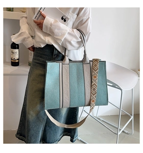 Détail du grand sac cabas en denim bleu clair avec bandoulière large et lettrage de marque