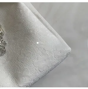 Détail du tissu jacquard floral blanc 3D avec chaîne en métal argenté élégante